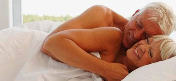 Pareja mayor abrazada en la cama sonriente