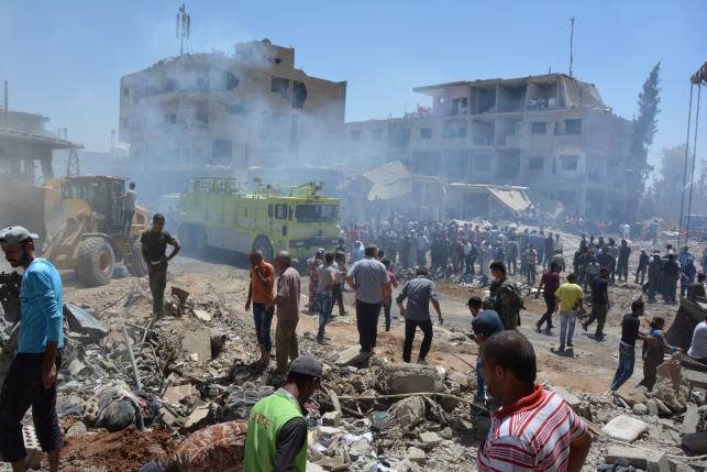 Smoke rises while people gather at a damaged site after two bomb blasts claimed by Islamic State hit the northeastern Syrian city of Qamishli near the Turkish border, Syria July 27, 2016. REUTERS/Rodi Said