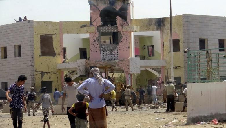 People gather at the scene following an attack by a suicide bomber who drove a car laden with explosives into a compound run by local militias in the port city of Aden, Yemen