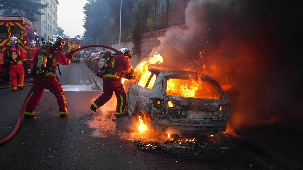 El deceso provocó conmoción y cólera en Nanterre. Bomberos apagan un auto incendiado